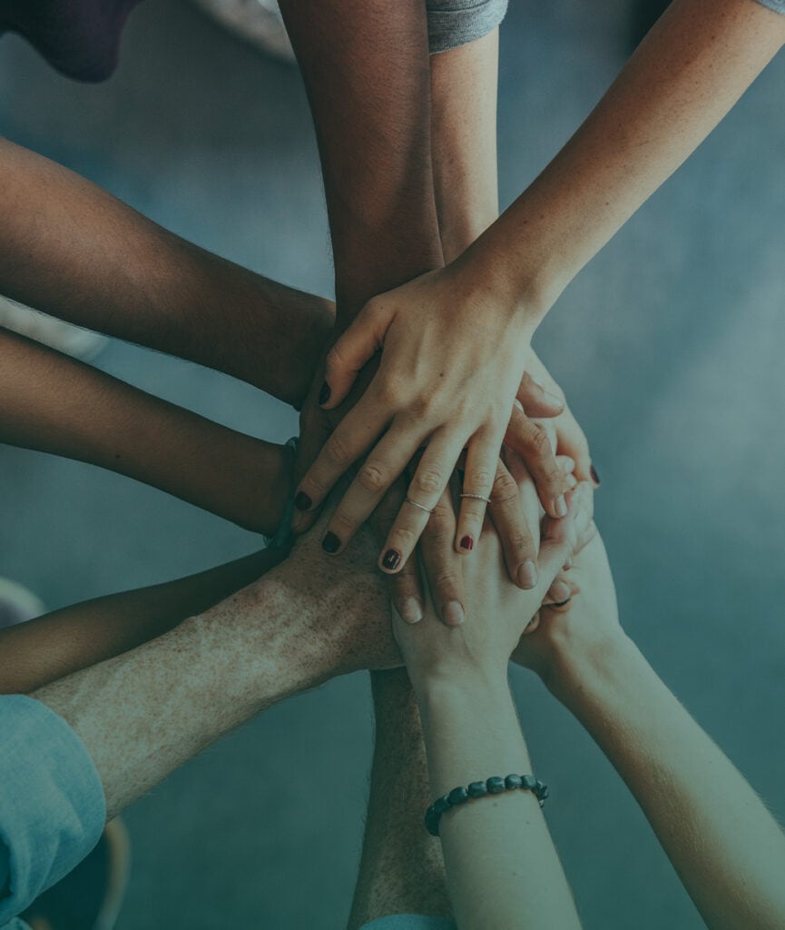 Diverse hands stacked together symbolizing fostering community support.