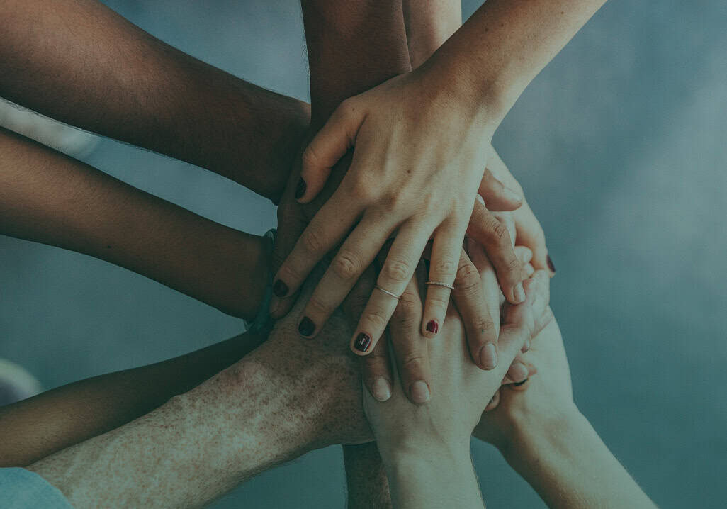 Diverse hands stacked together symbolizing fostering community support.