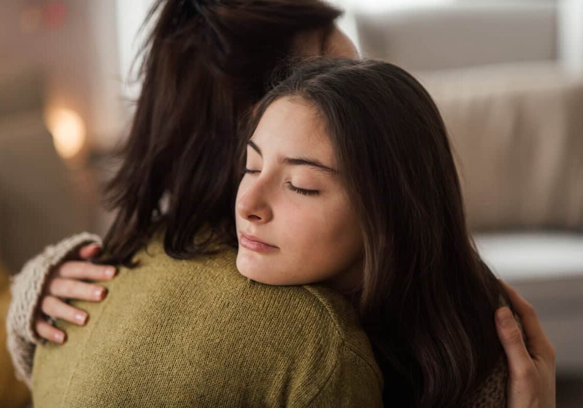 A teenage adopted daughter hugs her mother