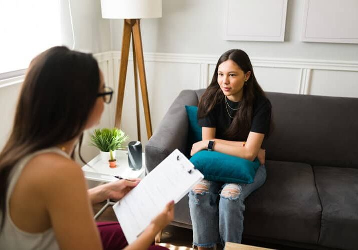 Woman in therapy session with counselor in a cozy office setting.